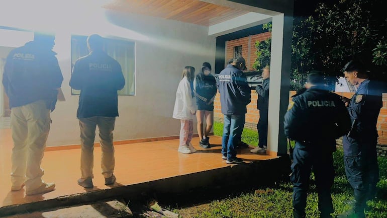 Agentes de policía en la escena del atraco, conversando con personas en una noche oscura, con luz limitada.