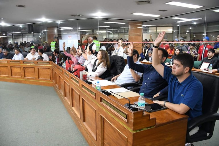 Juan Carlos Ozorio Admen, Rossana Rolon y Jesús Lara participan en la sesión levantando la mano, todos en un ambiente formal.