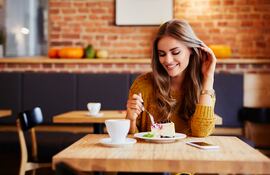 Mujer come un postre en una cafetería.