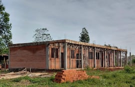 Construcción de ladrillos con varillas de metal expuestas en un entorno rural, sin personas presentes en la imagen.
