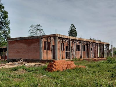 Construcción de ladrillos con varillas de metal expuestas en un entorno rural, sin personas presentes en la imagen.