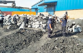 Empleados del puerto Terport de Villeta agrupan algunas de las bolsas con carbón vegetal almacenados en los contenedores de la red de tráfico de drogas.