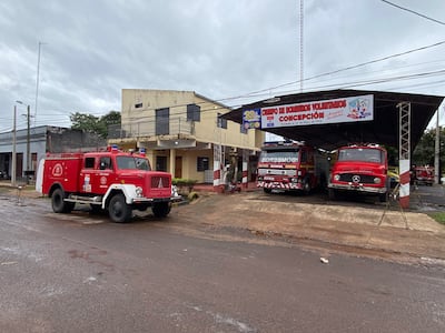 Dos camiones de bomberos, uno rojo y otro moderno, en el cuartel con cielo nublado de fondo.