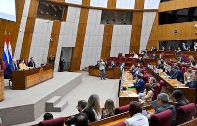 Óscar Lovera, vestido formalmente, habla en el estrado mientras otros asistentes lo observan en un ambiente de Congreso.