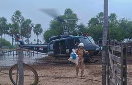 Un efectivo policial acerca una bolsa de alimento a pobladores aislados. Hasta el helicóptero tiene dificultad para bajar por la presencia de las aguas.