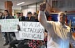 Grupo de personas protestando, con un hombre en traje oscuro y carteles que dicen 'NO A LA DICTADURA SINDICAL'.
