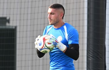 Arquero de la Albirroja con camiseta azul y pantalones negros, sosteniendo un balón, en campo de entrenamiento.