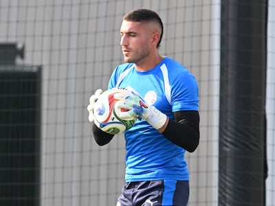 Arquero de la Albirroja con camiseta azul y pantalones negros, sosteniendo un balón, en campo de entrenamiento.
