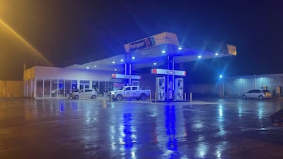 Estación de servicio Petropar iluminada por luces azules, con vehículos estacionados, incluido un automóvil policial.