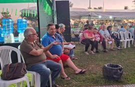Hombre canoso con gafas conversa en la Feria Che Sýpe guara, rodeado de personas en un ambiente relajado y festivo.