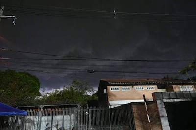 Cielo nublado y oscuro con cerca metálica en primer plano, reflejando la inminente tormenta en un área urbana vacía.