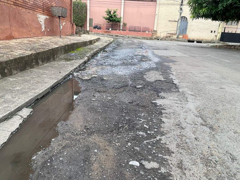 Calle en Tembetary con pavimento deteriorado, sin personas, y baches visibles sobre el asfalto.