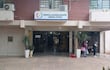 Entrada del Hospital Materno Infantil con dos figuras humanas, una habla y otra limpia con escoba, rodeados de vegetación.