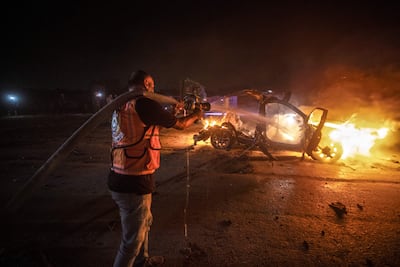 Personal de la Defensa Civil Palestina extingue un incendio en un automóvil destruido tras un ataque aéreo israelí en la carretera Al-Rashid, junto a la playa, en el sur de la ciudad de Gaza.