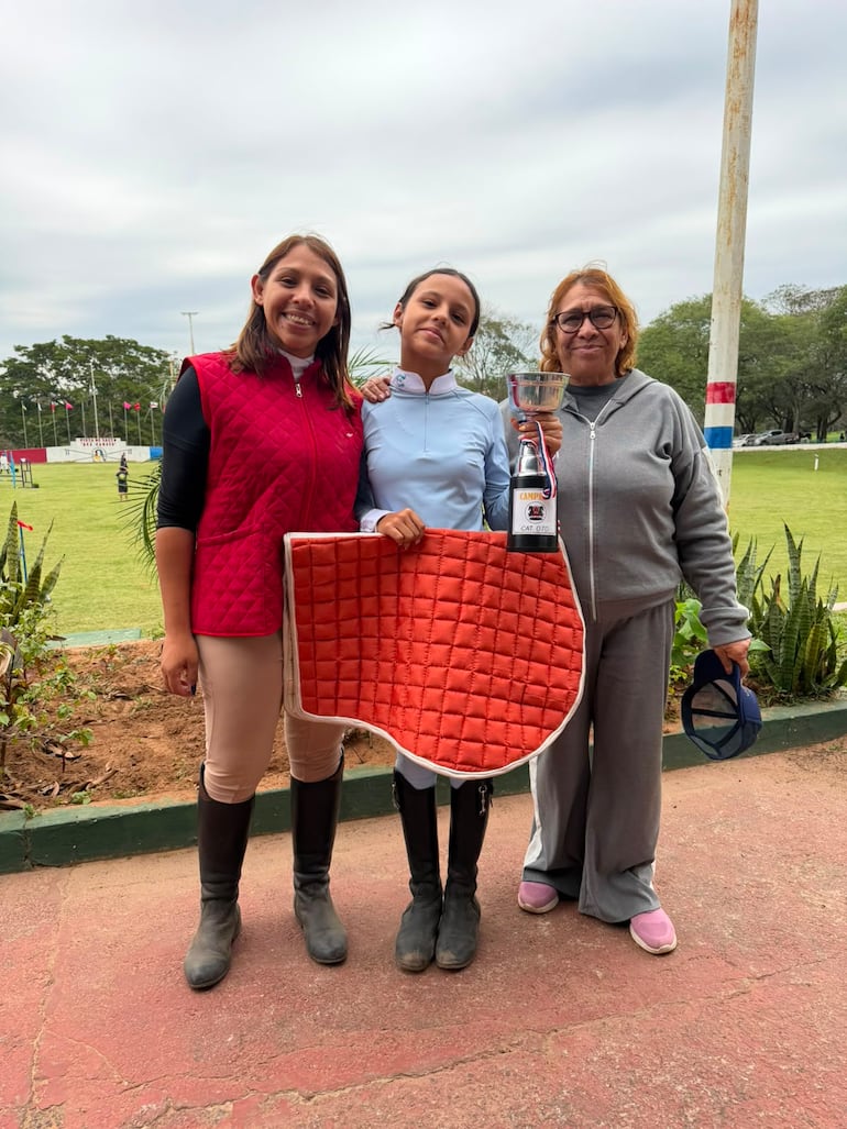 Ameli Domecq, ganadora de la categoría 0.70 metro, junto a su madre y abuela, luego de recibir su trofeo de campeona.