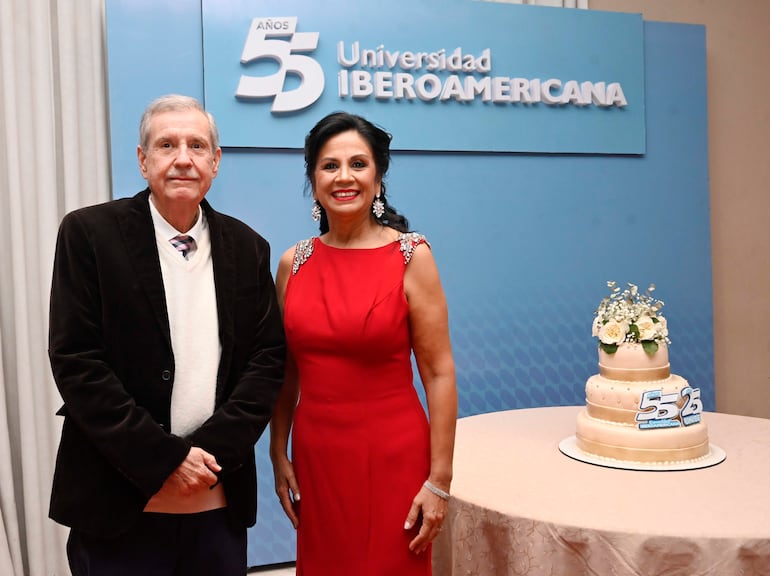 Dos mujeres sonríen, una con suéter claro y otra en vestido rojo, en ambiente festivo con pastel decorado.