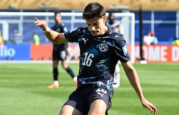 Damián Bobadilla en camiseta oscura con el número 16, concentrado en el tiro, rodeado de otros jugadores en el campo.