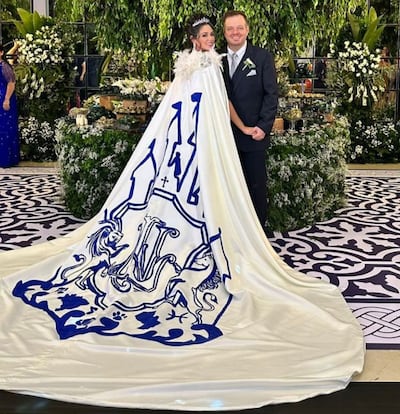 Natasha Zacarías con un capa en el vestido con una estampado de castillo e iniciales de la pareja. A lado está su esposo Luis Octavio López.