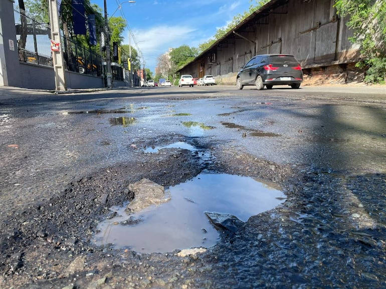 Bache con agua acumulada en la avenida Artigas, rodeado de vehículos y un cielo despejado en Asunción.
