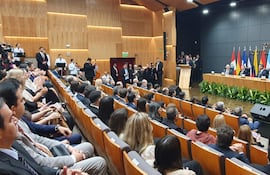Emiliano Rolón Fernández detrás de un podio, rodeado de hombres en traje en un ambiente formal con plantas decorativas.