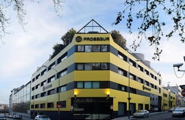 Edificio moderno de Prosegur en colores amarillos y negros, con vegetación en la azotea y coches estacionados.