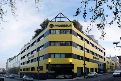 Edificio moderno de Prosegur en colores amarillos y negros, con vegetación en la azotea y coches estacionados.
