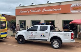 Dos hombres conversan cerca de una ambulancia del Cuerpo de Bomberos, en un entorno urbano con banderas paraguayas.