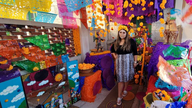 Una mujer posa en un altar de flores durante la celebración del "Día de Muertos" hoy, en Miami (Estados Unidos). Centenares de personas participaron este sábado en Coral Gables (Miami-Dade) en un festival por el Día de Muertos organizado por el consulado general en México en Miami en el que no faltaron los mariachis y las catrinas, además de la música, los bailes y la gastronomía de ese país de Norteamérica.
