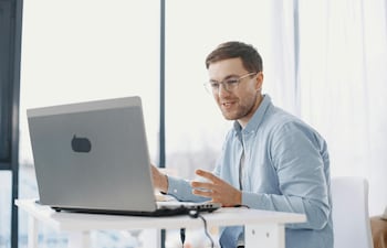 Un hombre sonríe mientras mirá la computadora, en un ambiente ejecutivo.