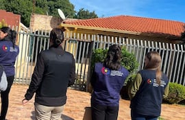 Cinco personas de espaldas, con chalecos de Vigilancia Sanitaria, observan un entorno residencial bajo un día soleado.