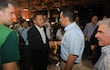 Miguel Prieto en traje oscuro y Ricardo Estigarribia en camiseta verde se saludan en un ambiente festivo con fondo de asistentes.