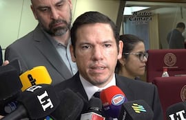 Alejandro Aguilera en traje oscuro, dirigiéndose a un grupo de periodistas en conferencia de prensa, con expresión seria.