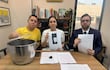 Johanna Ortega en blusa blanca sostiene un documento, mientras Bruno Martinez en camiseta amarilla y Maximiliano Seiferheld en traje oscuro observan atentos.