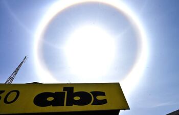 Cielo despejado con un halo alrededor del sol y letrero de 'abc' en la parte inferior, junto a una torre de transmisión.