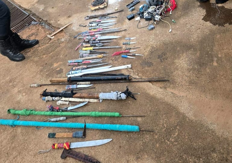 Armas blancas y objetos metálicos dispuestos en cemento, sin personas visibles, en un contexto de requisa.