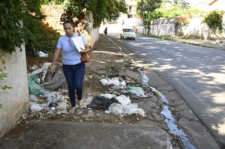 Ciudadana camina en medio de un vertedero sobre Primero de Marzo casi Cacique Lambaré, a pasos de la Municipalidad de esa ciudad.