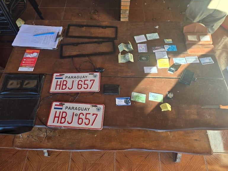 Sobre una mesa, matrículas HBJ 657 y documentos en un entorno interior iluminado y ordenado.