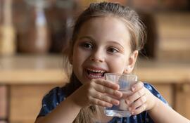 una niña toma un vaso de agua