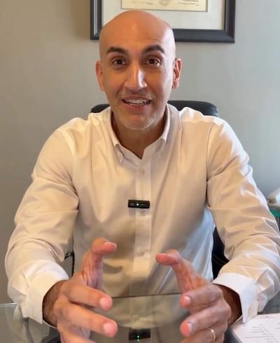 Julio Mazzoleni, con camisa blanca y expresión amigable, gesticula con las manos en una oficina con documentos sobre la mesa.