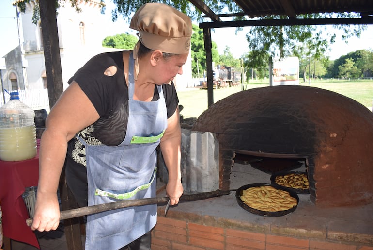 La chipera Ana Estigarribia retira las asaderas con chipas del horno.