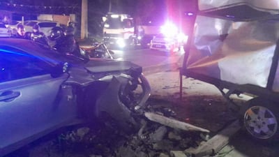 Tres personas con cascos evalúan un vehículo dañado en la noche, rodeados de escombros y luces de emergencia.