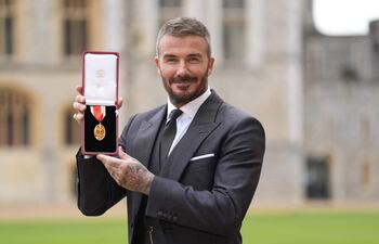 David Beckham muestra orgulloso su medalla tras ser nombrado Caballero en una ceremonia de investidura en el Castillo de Windsor.