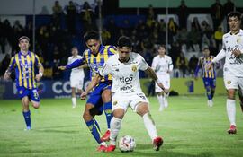 El mediocampista de Guaraní, Aldo Maíz protege el esférico ante la presión de volante del Sportivo Luqueño, Víctor Sebastián Quintana.