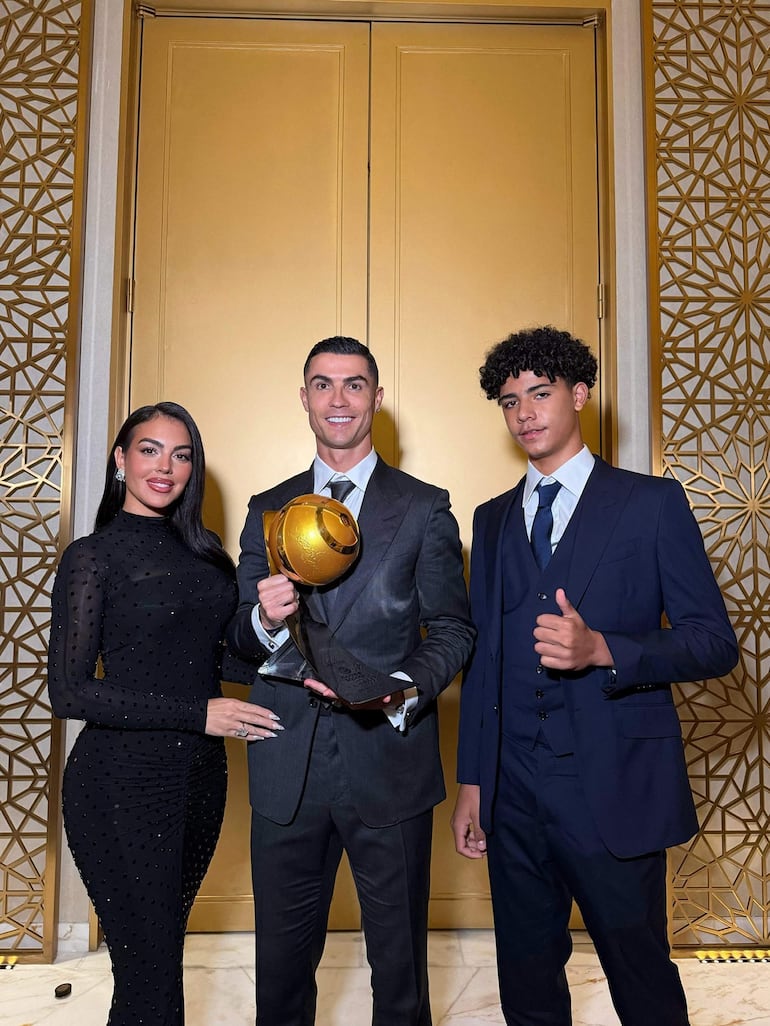 Mujer en vestido negro elegantemente posada, hombre en traje gris sonriendo con trofeo dorado y joven con gesto de pulgar arriba.