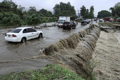 Residentes hondureños transitan por una creciente de agua de una quebrada hoy en la ciudad de San Pedro Sula (Honduras).