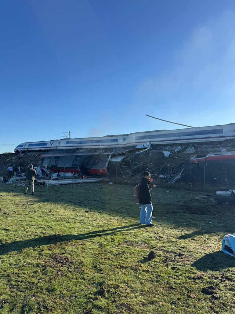 Rodrigo Fernández Andés, joven con mochila oscura, observa el accidente ferroviario mientras sujeta su teléfono móvil.