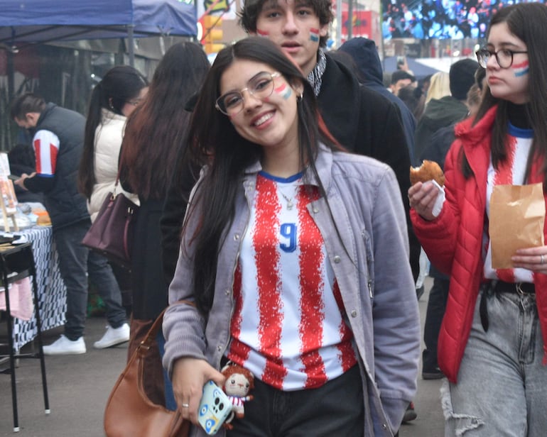 Jóvenes sonrientes con camisetas rojas y blancas, ambiente festivo en la calle Mariscal Estigarribia decorada.