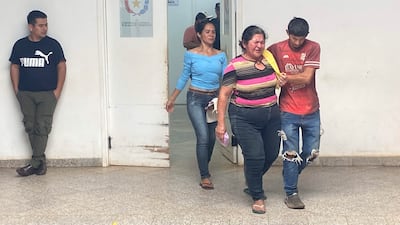 Tres mujeres y un hombre, todos vistiendo ropa oscura, expresan tristeza en un ambiente serio, posiblemente un edificio público.