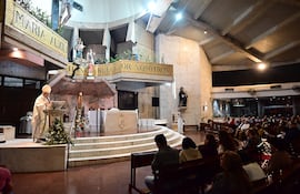 El arzobispo en alba y estola blanca, frente al altar, con una congregación atenta en una iglesia moderna y iluminada.