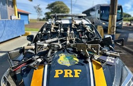 Vehículo patrullero de la Policía Federal con varias armas de fuego sobre su capó en un ambiente exterior.
